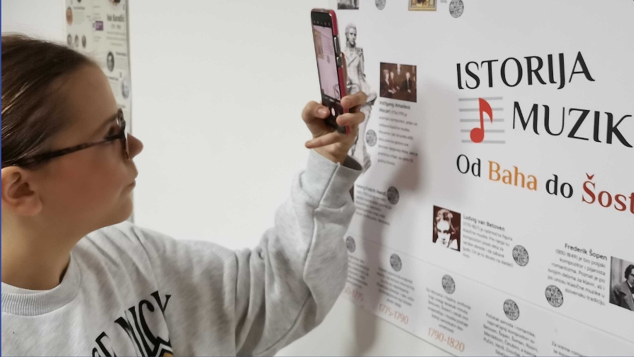 A pupil scanning a MapApp interactive poster on a classroom wall with a phone